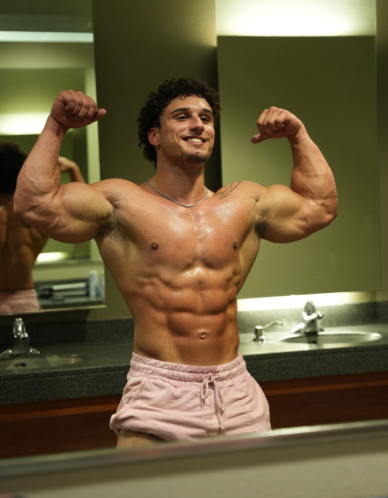 Coach is flexing his arms and smiling.